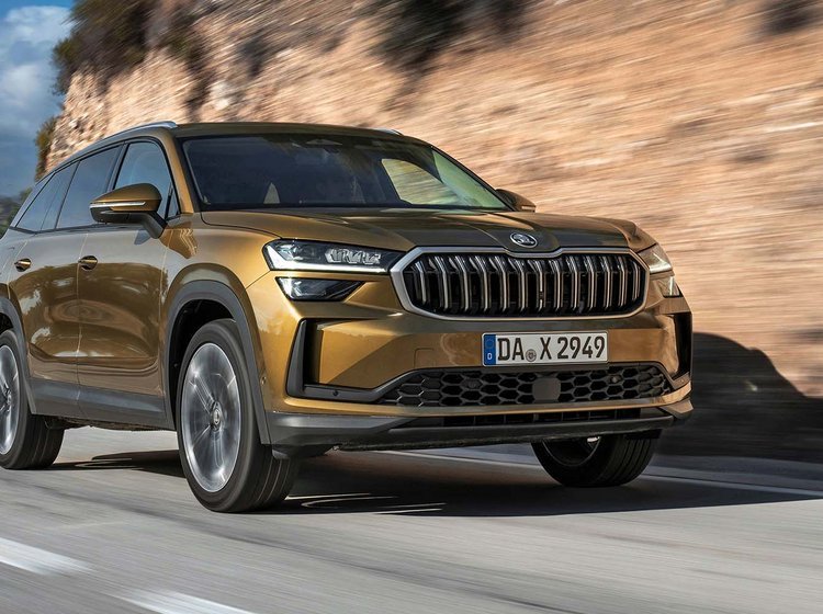 Guldfarvet Skoda Kodiaq kører i sving med bjerg i baggrunden