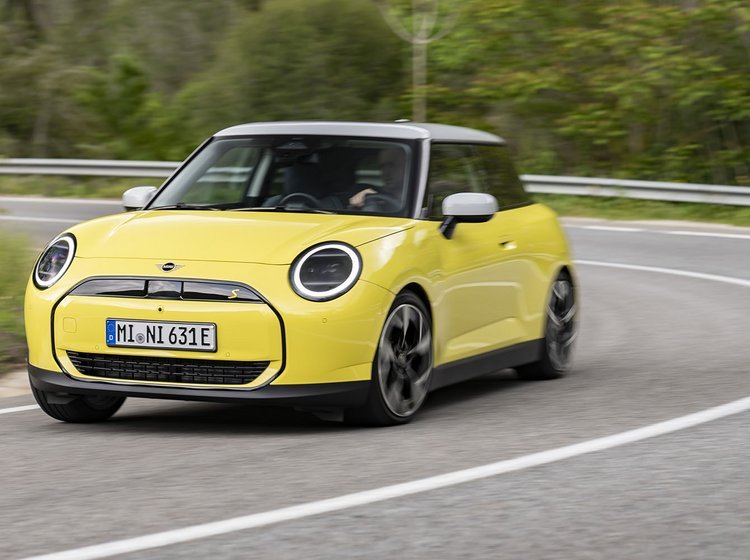 Gul Mini Cooper kører i et sving på en vej