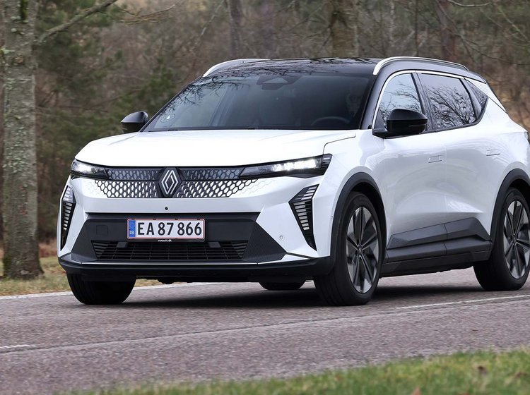 Renault Scenic set skråt forfra, mens den kører på vej med træer rundt om