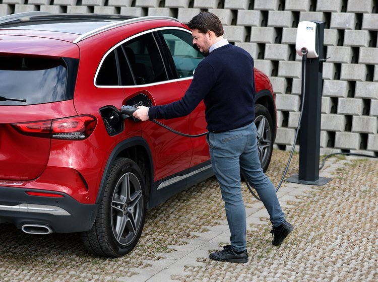 Mand sætter ladestik i rød plugin-hybrid.