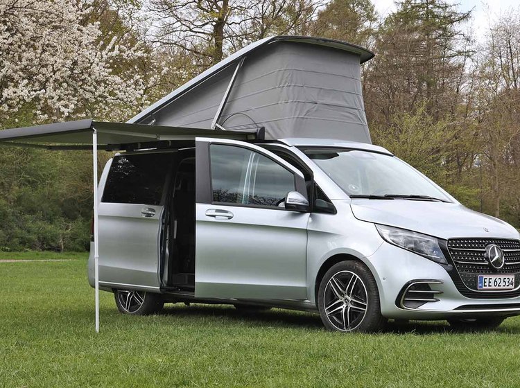 En Mercedes-Benz Marco Polo står på en græsplæne med taget slået op.
