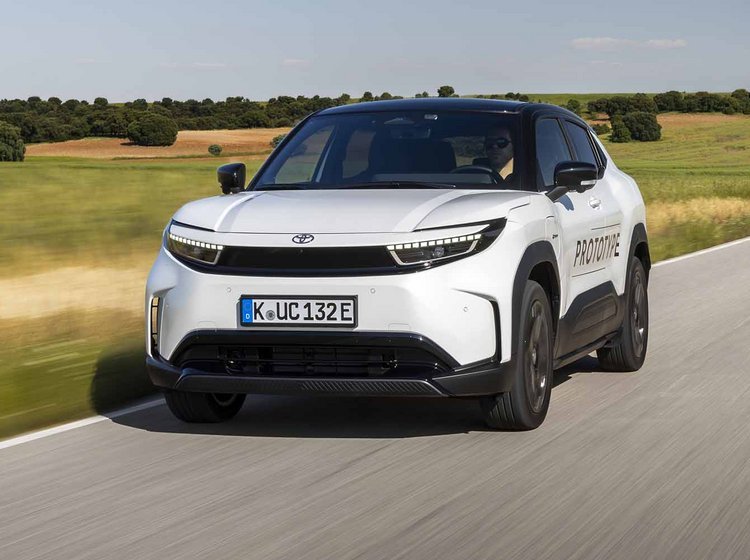 Hvid Toyota Urban Cruiser kører på vej med marker i baggrunden