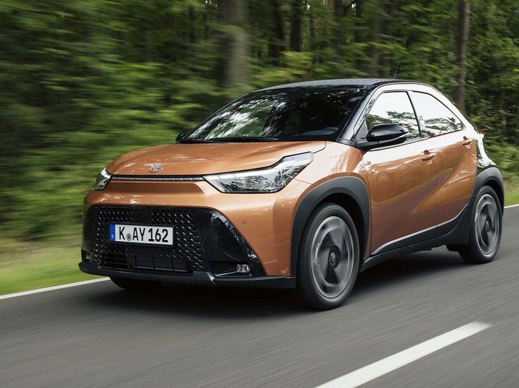 Toyota Aygo X set skråt forfra, mens den kører med træer i baggrunden