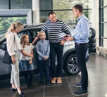 Familie taler med en bilhandler om at købe ny bil. 