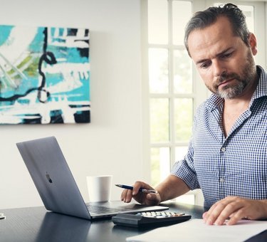 Mand sidder ved desktop og kigger i papirer