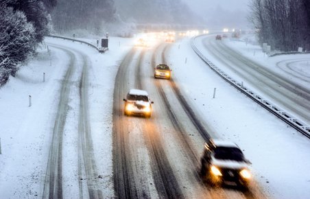 Biler kører på snedækket motorvej. 