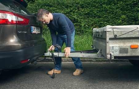 Mand kobler trailer til sin bil. 