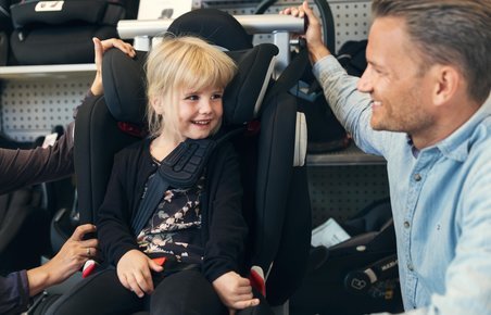 Barn prøver at sidde i en autostol i en butik inden køb. 