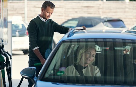 Mand er ved at tanke sin bil på en tankstation. 