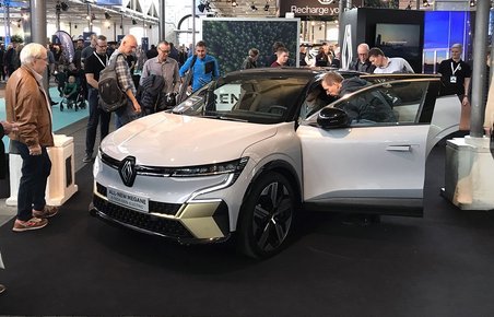 Publikum betragter hvid elbil med åben fordør på messen eCarExpo.