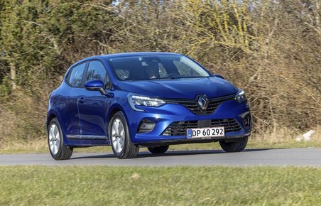 En blå Renault Clio kører på en landevej med træer i baggrunden