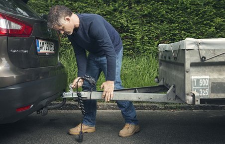 Mand sætter trailer på en bil