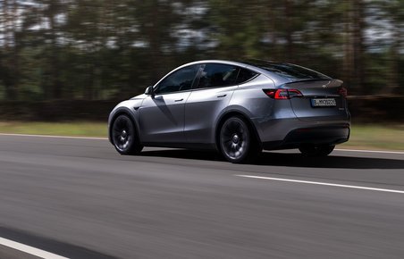 En grå Tesla Model Y kører på en vej. 