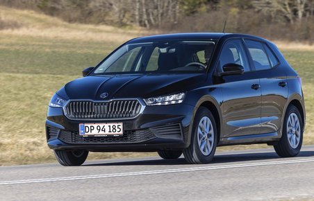 En sort Skoda Fabia kører på en landevej med græs i baggrunden