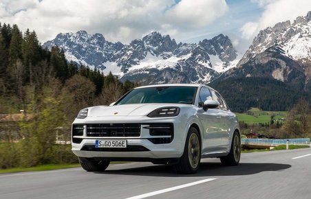 HVis Porsche Cayenne i fart på landevej med bjerge i baggrunden