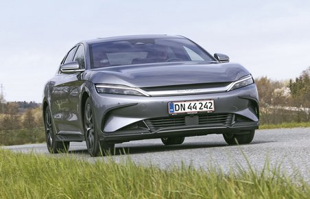 Elbilen BYD Han set forfra, mens den kører på en landevej med græs i forgrunden