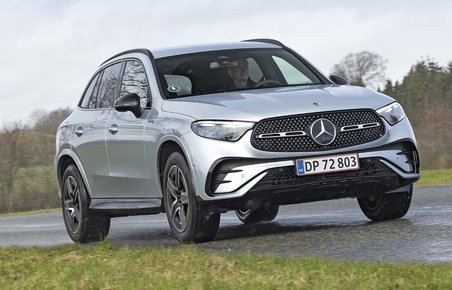 En sølvgrå Mercedes GLC kører på en landevej med skov i baggrunden