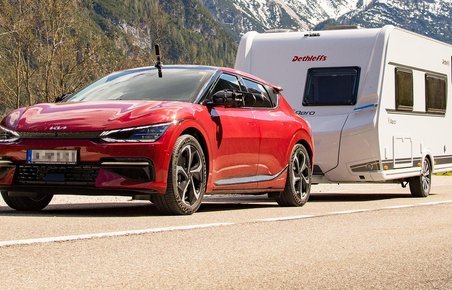 Kia EV6 trækker en campingvogn i bjergene. 
