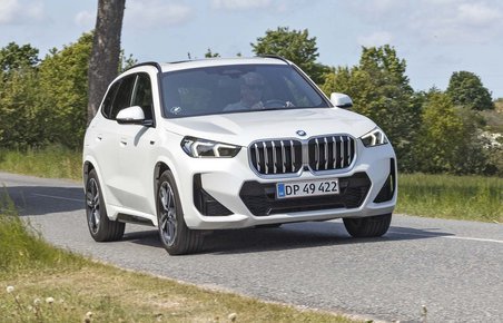 En hvis BMW X1 kører på en landevej med træer i baggrunden