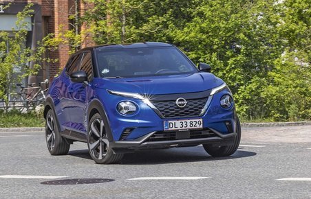 En blå Nissan Juke drejer ud på en asfaltvej