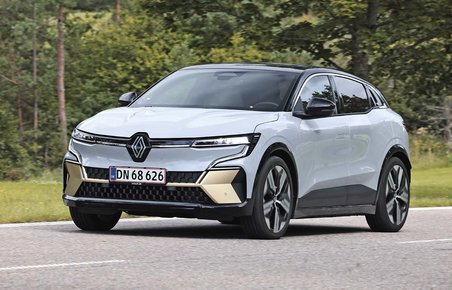 Elbilen Renault Megane E-Tech set skråt forfra, mens den kører på en vej med træer i baggrunden.