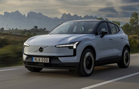 Elbilen Volvo EX30 kører på vej med bjerge i baggrunden.