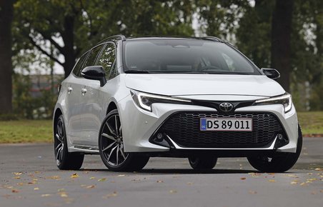En hvid Toyota Corolla set forfra, mens den holder foran træer