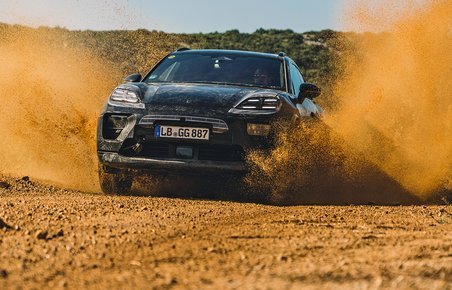 Porsche Macan forfra med sand, der flyver op fra hjulene.
