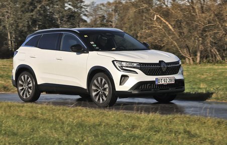 En hvid Renault Austral kører på en landevej med træer i baggrunden