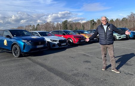 Person står foran 7 biler, der konkurrerer om at blive Car of the Year 2024