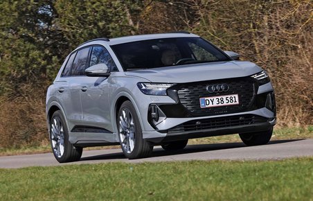 En Audi Q4 e-tron kører på en landevej med græs i forgrunden