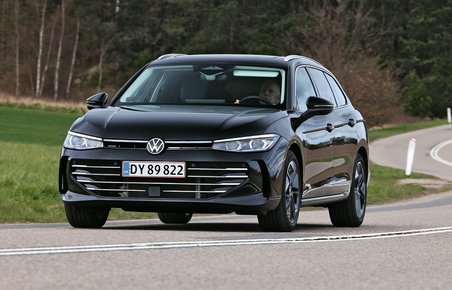 En sort VW Passat kører gennem et sving med skov i baggrunden