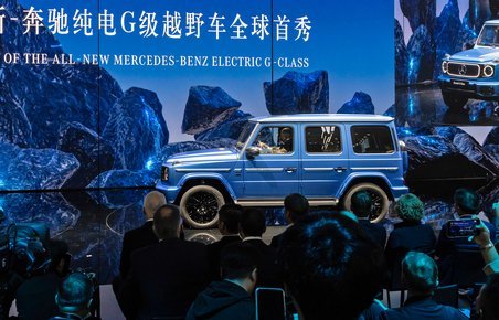 Blå Mercedes G-klasse med tilskuere i forgrunden. 