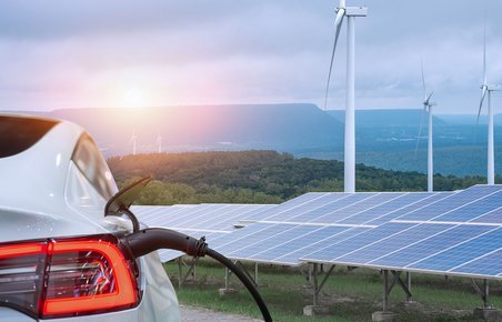 Elbil lader. I baggrunden er der vindmøller og solceller