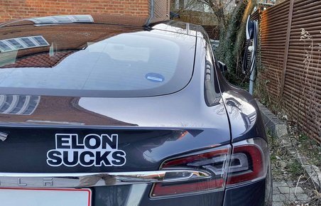 Tesla Model S med "Elon Sucks"-mærkat parkeret i indkørsel