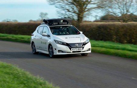 Hvid Nissan på lille vej med stor tagboks.