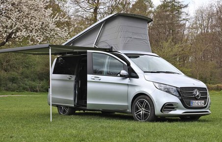 En Mercedes-Benz Marco Polo står på en græsplæne med taget slået op.
