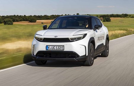Hvid Toyota Urban Cruiser kører på vej med marker i baggrunden