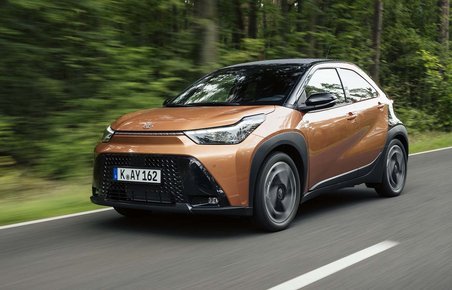 Toyota Aygo X set skråt forfra, mens den kører med træer i baggrunden